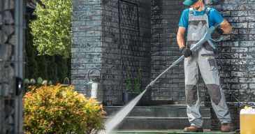 Driveway Pressure Washing. Caucasian Worker Cleaning Area in Front of the House.